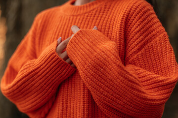 Fashion details of warm knitted orange sweater, cozy autumn clothes concept