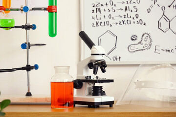 Modern microscope, chemical flasks and protective mask on table in teenager's room