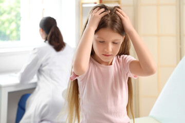 Little girl with pediculosis scratching in clinic