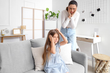 Little girl with pediculosis scratching her head and her worried mother at home