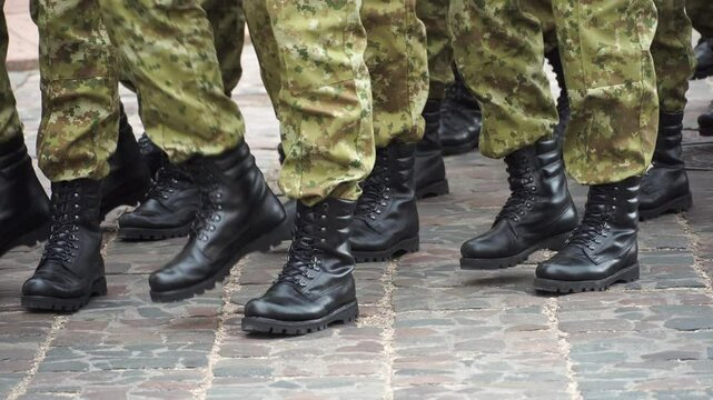 A military formation marches on parade. The soldiers are marching in formation. Military boots and uniforms of soldiers in close-up.