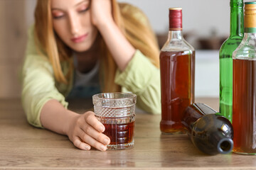Young woman drinking alcohol at home. Concept of alcoholism