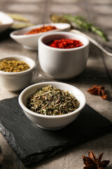 Bowls of different aromatic spices on grunge tile table
