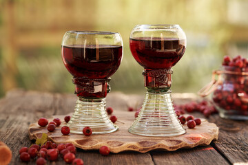 Two glasses of medicinal wine with fresh hawthorn berries on a table outdoors