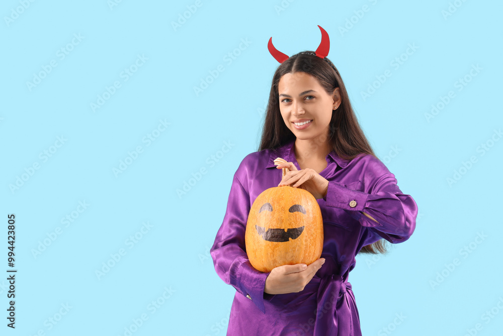 Canvas Prints Young woman with Halloween pumpkin on blue background