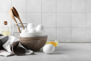 Bowl with raw chicken eggs on white table