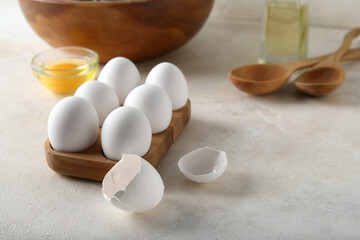 Wooden holder with raw chicken eggs on white background