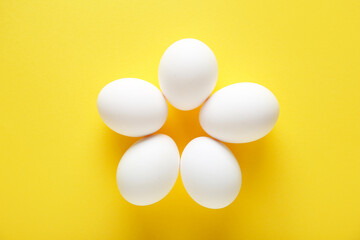 Raw chicken eggs on yellow background