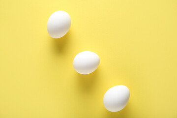 Raw chicken eggs on yellow background