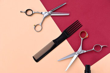 Fototapeta premium professional hairdressing scissors and comb on a pink burgundy background closeup