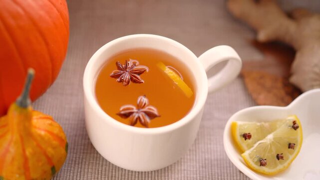 Hot tea with lemon, cloves and cinnamon stiring by a woman's hand whith golden spoon. Cozy atmosphere at home on a warm autumn day. 4k