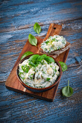 Fresh Provence spread with fresh goat's cheese, chopped shallots and herbs served as close-up in a bowl on a wooden board