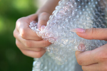 Female hands popping the bubbles in bubble wrap