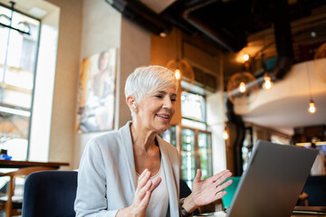 Senior businesswoman having video call on laptop in cafe