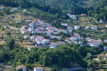 Vista panorâmica da Serra da Estrela, com seus imponentes picos rochosos, vastos campos verdes e céu claro, oferecendo uma paisagem tranquila e natural da maior montanha de Portugal.