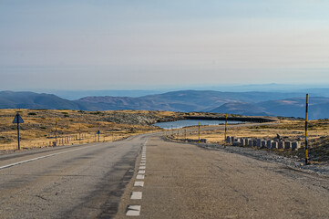 Vista panorâmica da Serra da Estrela, com seus imponentes picos rochosos, vastos campos verdes e céu claro, oferecendo uma paisagem tranquila e natural da maior montanha de Portugal.