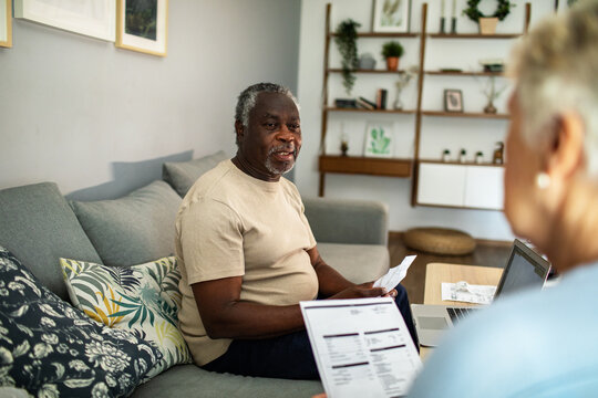 Diverse senior couple reading bills on the couch at home