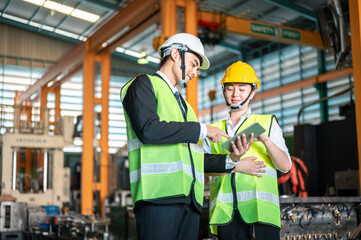 technician, safety, industrial, distribution, manufacturing, discussion, foreman, facility, warehouse, hard hat. Two men in safety gear are looking at a tablet. One of them is smiling.