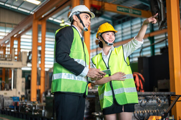 mechanic, safety, maintenance, manufacturing, machinery, machine, expertise, hard hat, hardhat, helmet. Two people in safety gear, one pointing at something. Scene is serious and focused.