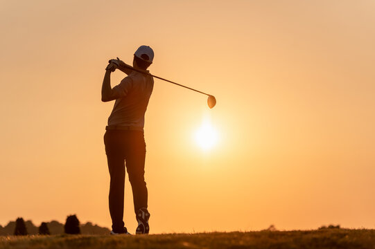 fairway, golf, golf course, golfer, hit, silhouette, tee, course, competition, sunset. A man is swinging a golf club at a ball on a golf course. The sun is setting in the background.