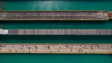 People walking across, people displacement, people commuting in bridge road over lake or sea