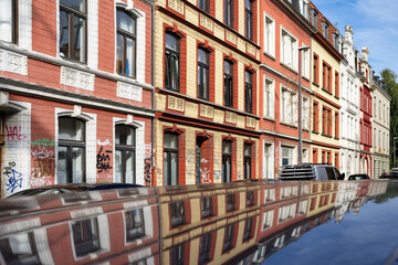 a long row of typical simple workers' houses from the founding era in warm pastel colors in cologne ehrenfeld