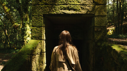 Woman Walking into Moss-Covered Stone Ruin in Enchanted Forest