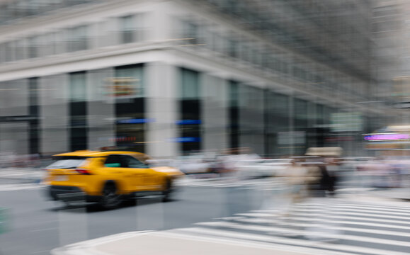 Blurred yellow taxi crossing street in New York City