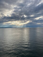 Fototapeta premium Sun rays through the clouds over a calm sea