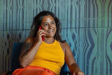 Woman in yellow tank top chatting on red phone