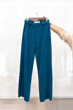 Woman displaying a pair of teal pants on a hanger