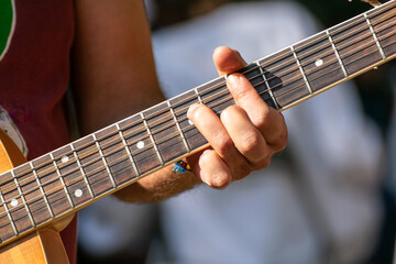 fingers of a man's hand playing a tone on a Spanish guitar in a outdoor party, music concept