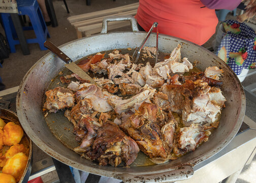 A large dish of Hornado, a traditional roast pork dish in Ecuador, sold at food stands in local markets. In most of these places, the pork was roasted whole in a large clay oven outdoors.