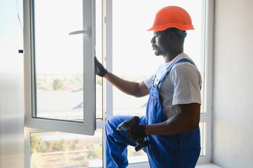 Worker installing plastic window indoors