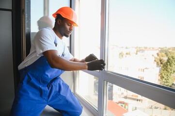Worker installing plastic window indoors