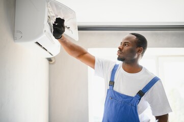 Young African Male Technician Repairing Air Conditioner