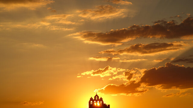 Silhouetted building against vibrant sunset with dynamic clouds