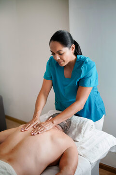 Female massage therapist giving back massage to male client