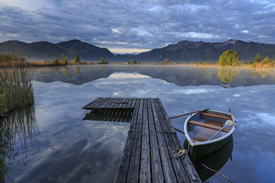 Mountains reflected in lake, jetty and boat, morning light, spring, Loisach-Lake Kochel moor, Bavaria, Germany, Europe