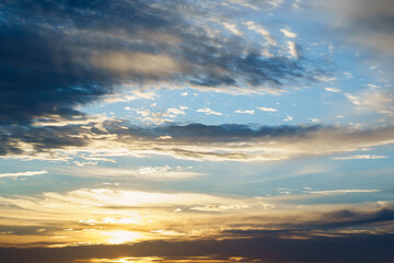 Obraz premium Golden sunlight breaks through layers of dark and light clouds in a vast sky.