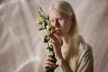 Medium closeup studio portrait of young Caucasian woman with albinism posing for camera with...