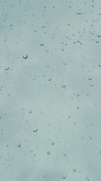 Vertical video of a rain drops on a window and grey clouds