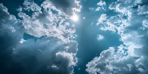 Fototapeta premium A vibrant blue sky filled with fluffy white clouds, with the sun shining brightly through the gaps.