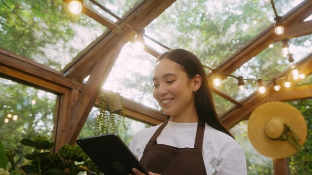 Smiling brunette standing under bright garland with tablet
