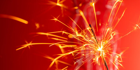 Beautiful glowing sparklers on colored background. Colorful sparklers sparkling against vibrant red bokeh background, creating festive and celebratory atmosphere. Christmas mood, festive red backgroun