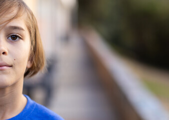 In school, boy standing outside, looking at camera with serious expression, copy space