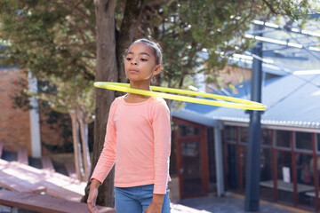 Hula hooping, african american girl in schoolyard enjoying outdoor activity during break