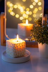 Soy wax candle in front of a mirror. Reflection of candlelight and cozy atmosphere. Home decor. Inspirational spiritual concept