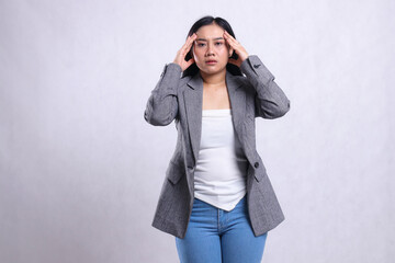expression of beautiful young office woman weak dizzy both hands holding head wearing gray suit and...