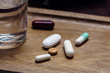 Close-up of assorted medication with water on wooden surface